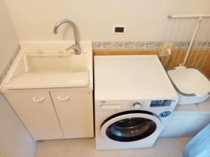 a small kitchen with a washing machine and a sink at B&B Il Sentiero in San Sperate