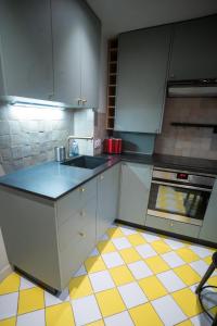 a kitchen with white cabinets and a yellow and white tiled floor at Stuart in Dinard