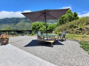 a table and two chairs with an umbrella at Le Refuge d'Heva in Salazie