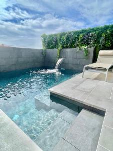 una piscina con una silla y una cascada en The Retreat House - Private Pool, en Puerto de Santiago