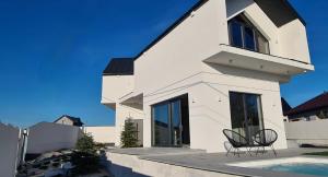 a white house with two chairs and a swimming pool at Villa Blanca in Cedzyna