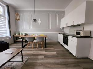 Downtown Apartments Bilk في دوسلدورف: مطبخ مع دواليب بيضاء وطاولة مع كراسي