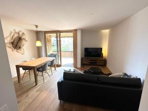 sala de estar con sofá negro y mesa en Beautiful Sunny New 1 Bed Apt (2.5Zim). Ski in/out, en Flims