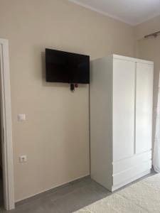 Harmony Apartments في سارنده: خزانة بيضاء مع تلفزيون بشاشة مسطحة على الحائط