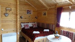 a bedroom with a bed in a log cabin at Cabanuta Casuta din Povesti in Bran