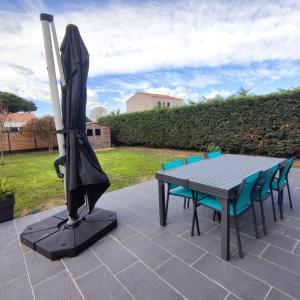 a table and chairs and an umbrella on a patio at 003 QUIN - Maison du Maine in Grand-Village-Plage