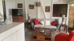 ein Wohnzimmer mit einem Sofa und einem TV in der Unterkunft Villa Pelican Lodge in Deshaies