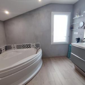 003 QUIN - Maison du Maine في Grand-Village-Plage: حمام أبيض مع حوض استحمام ونافذة