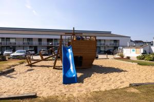 un parque infantil con un tobogán azul en la arena en John Yancey Oceanfront Inn, en Kill Devil Hills