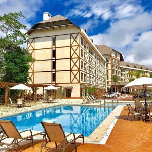 a hotel with a pool and chairs and a building at Flat Pedra Azul - hospedagem nas montanhas in Pedra Azul