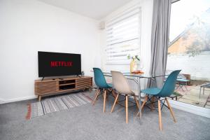 a living room with a tv and a table and chairs at K Suites - Selkirk Street in Cheltenham