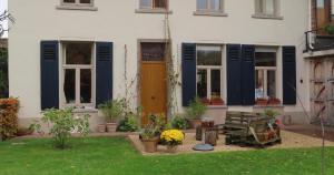 a house with blue shutters and a bench in a yard at Authentieke privé-kamer bij Karen in Beveren