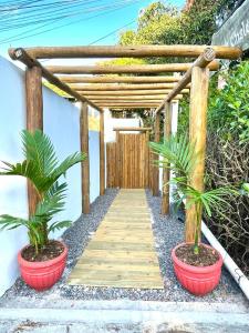 a wooden pathway with two potted plants and a wooden pergola at Vila Vasconcelos in Itacaré