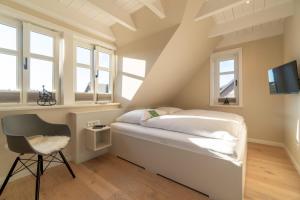 - une chambre avec un lit, une chaise et des fenêtres dans l'établissement Hus Sünneck, à Wyk auf Föhr