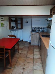 eine Küche mit einem roten Tisch, einem roten Tisch und einem Kühlschrank in der Unterkunft Gite de la tour in Plancherine
