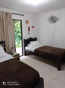 a bedroom with two beds and a sliding glass door at Posada Miss Mazie in San Andrés