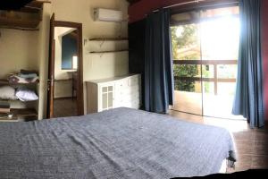 1 dormitorio con 1 cama y puerta que da a un patio en Nova Casa Laranjeiras, en Garopaba