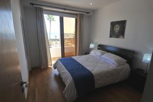 een slaapkamer met een bed en een raam met uitzicht bij Ithaki Phinikoudes Apartment No. 102 in Larnaka