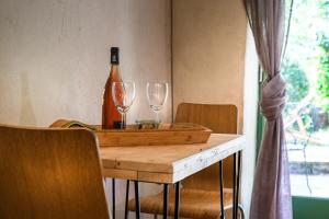 een fles wijn en twee wijnglazen op een tafel bij Les chambres de la Dourbie in Nant