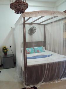a bedroom with a canopy bed with white curtains at Yunal's Place in Matara