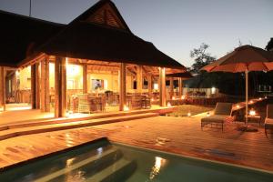 a house with a pool and a deck with an umbrella at Fathala Wildlife Reserve in Toubakouta