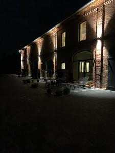 un bâtiment éclairé la nuit avec des chaises devant dans l'établissement Ferienwohnung 1 am Herrenhaus Ahrensbök, à Ahrensbök