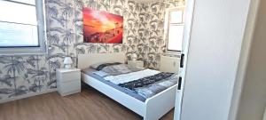 1 dormitorio con 1 cama con una pintura en la pared en Lake FeWo Santorini en Oberteuringen