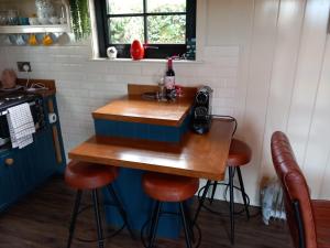 a small kitchen with a table with stools at Delightful Shepherds Hut in Westport