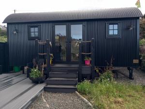 a black tiny house with stairs leading to the door at Delightful Shepherds Hut in Westport