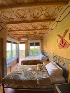 1 dormitorio con 2 camas y techo de madera en La Petite Gorge, Hôtel & Restaurant Todra Gorge, en Tinerhir