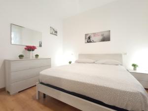 a white bedroom with a bed and a dresser at Dietro Piazza in Ascoli Piceno