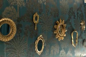 un mur avec des miroirs en or sur papier peint bleu dans l'établissement Reglisse et Pain d'Epices - Chambres d'hôtes, à Honfleur