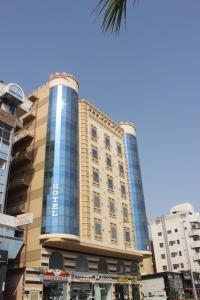 a tall building with blue windows in a city at التميز الراقي - الفيصلية in Jeddah