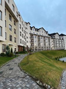 Un gran edificio de apartamentos con un parque enfrente. en Apartmani Fashion -Milmari Resort, en Kopaonik