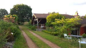 a dirt road leading to a house with a table and chairs at Clos de l'Arthonnet- Chambres d'hôtes avec cuisine d'été, proche Limoges in Flavignac