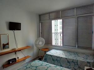 um quarto com uma cama e uma janela com uma ventoinha em Apto 1 dorm. Guarujá - Pitangueiras - perto da praia no Guarujá