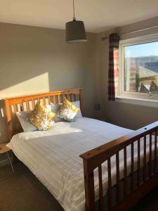 een slaapkamer met een bed met kussens en een raam bij Dunfermline Home with Free Parking Near Amazon & M90 in Dunfermline