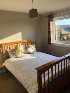 ein Schlafzimmer mit einem Bett mit Kissen und einem Fenster in der Unterkunft Cosy Home with Free Parking Near Edinburgh St Andrews M90 & Amazon in Dunfermline