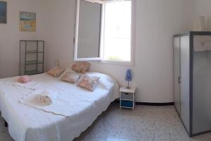 Un dormitorio con una cama blanca con almohadas y una ventana en Banyuls vu d'en haut : appartement T3 spacieux, en Banyuls-sur-Mer