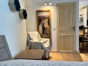 Studio cosy et fonctionnel entre Saule et Lilas في فيلارد دي لانس: غرفة نوم بها كرسي و لوحة على الحائط