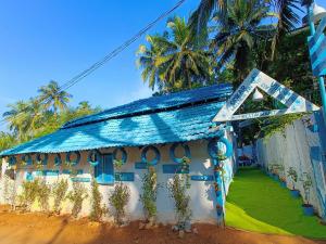 a blue and white building with palm trees in the background at Omkar wellness inn in Arambol