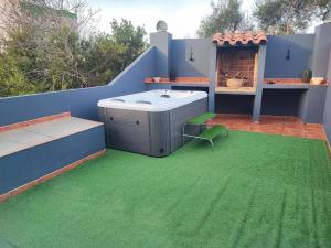 um pátio com uma banheira de hidromassagem e relva verde em Casa vacacional Lavernia em Cabanes