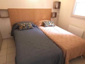 łóżko z dwiema poduszkami w pokoju w obiekcie LE PIERANI - A 90m de la mer w mieście Saint-Hilaire-de-Talmont