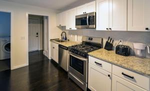 a kitchen with white cabinets and a stove top oven at Modern Two Bedroom Condo - Boston in Stoneham