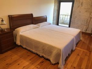 łóżko w sypialni z drewnianą podłogą w obiekcie Casa Lisboana w mieście Pontevedra