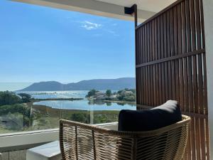 a balcony with a chair and a view of a lake at Golden Tulip Porto-Vecchio in Porto-Vecchio