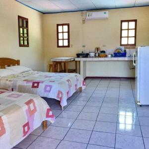 a room with two beds and a kitchen with a refrigerator at Hotel Moctezuma in Montezuma