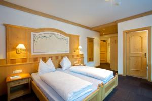 1 dormitorio con 1 cama grande con almohadas blancas en Hotel B&B Pardeller en Nova Levante