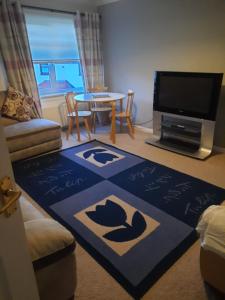 a living room with a table and a tv at Ardfern Apartments in Airdrie