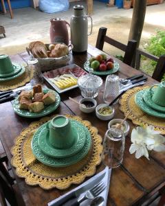 una mesa de madera con platos verdes y comida. en Mandala Camping Pousada, en Florianópolis